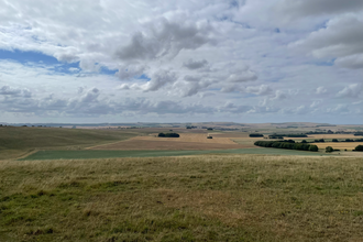 Landscape view of farmland over a vast valley, with blue cloudy sky