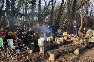 Group of men sit around campfire