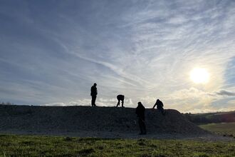 A silhouette of 4 people on top of butterfly bank with sun in background