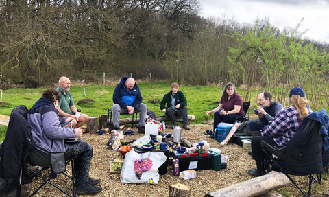 Group of men and women sat round campfire