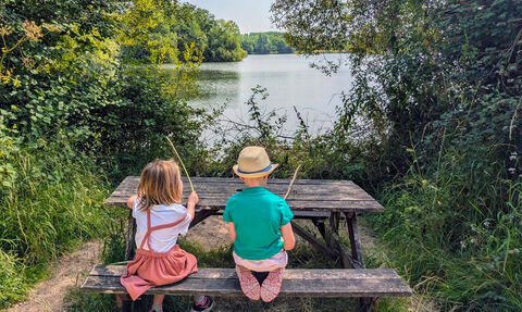 Two kids sitting on a bench overlooking lake at Lower Moor