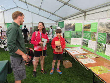 A lady and boy talk to WWT staff in a big marquee about one of our conservation projects