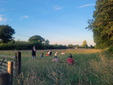 A group of men sat in a field with golden light from the sun going down