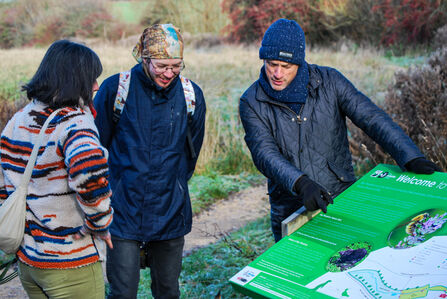 Three people looking at an information board