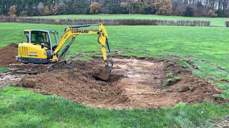 Digger digging a shallow hole in a field