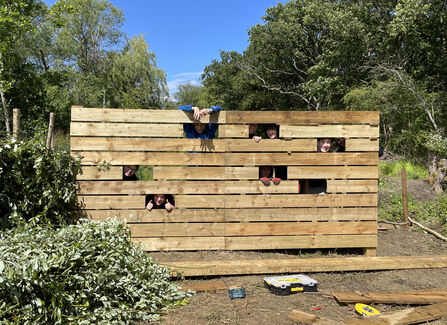 Young people peek through the slots in newly constructed bird viewing screen.