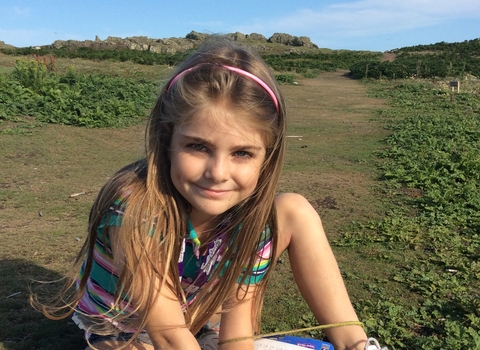 Grace sits in the grass with flowers