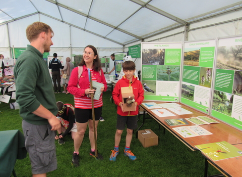 A lady and boy talk to WWT staff in a big marquee about one of our conservation projects
