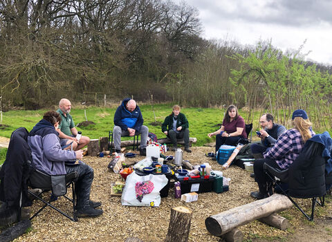 Group of men and women sat round campfire